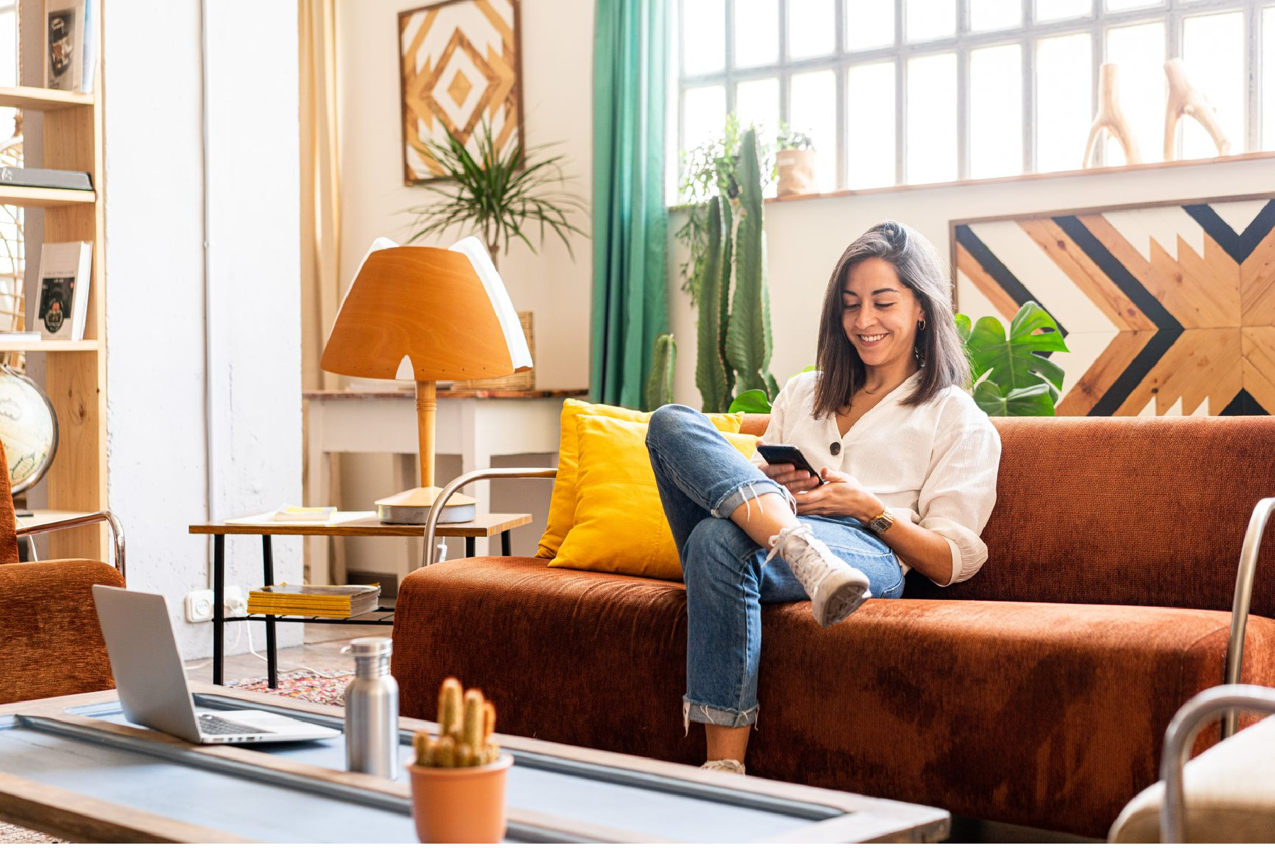 Woman sitting on couch with cell phone in hand