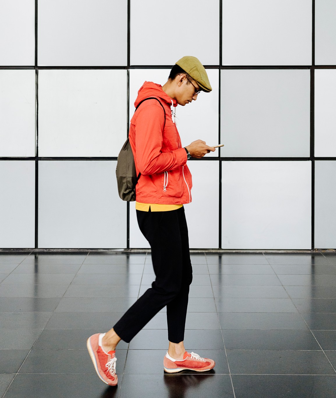 Gehender junger Mann mit Smartphone, auf das er schaut